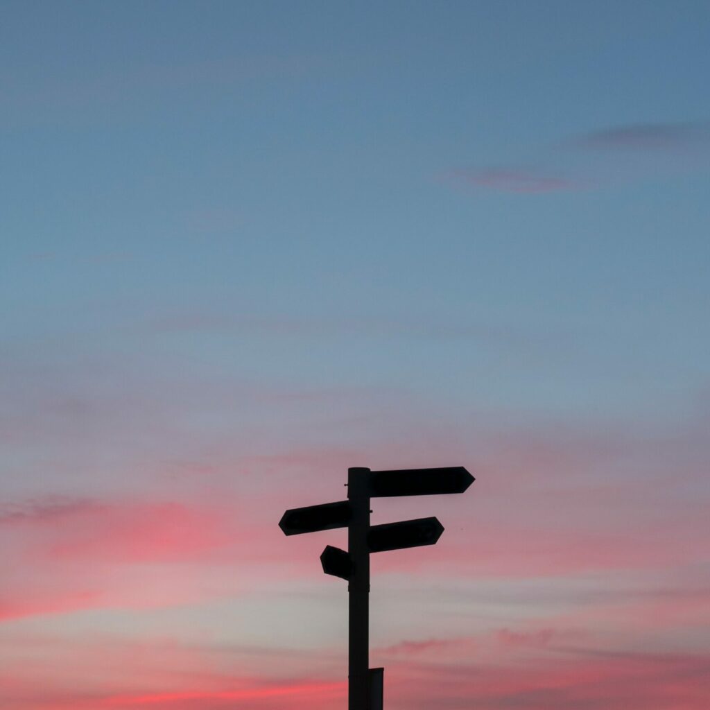 stock image depicting directional signage and blue and pink sky for an article about doing business in the Spanish speaking market.