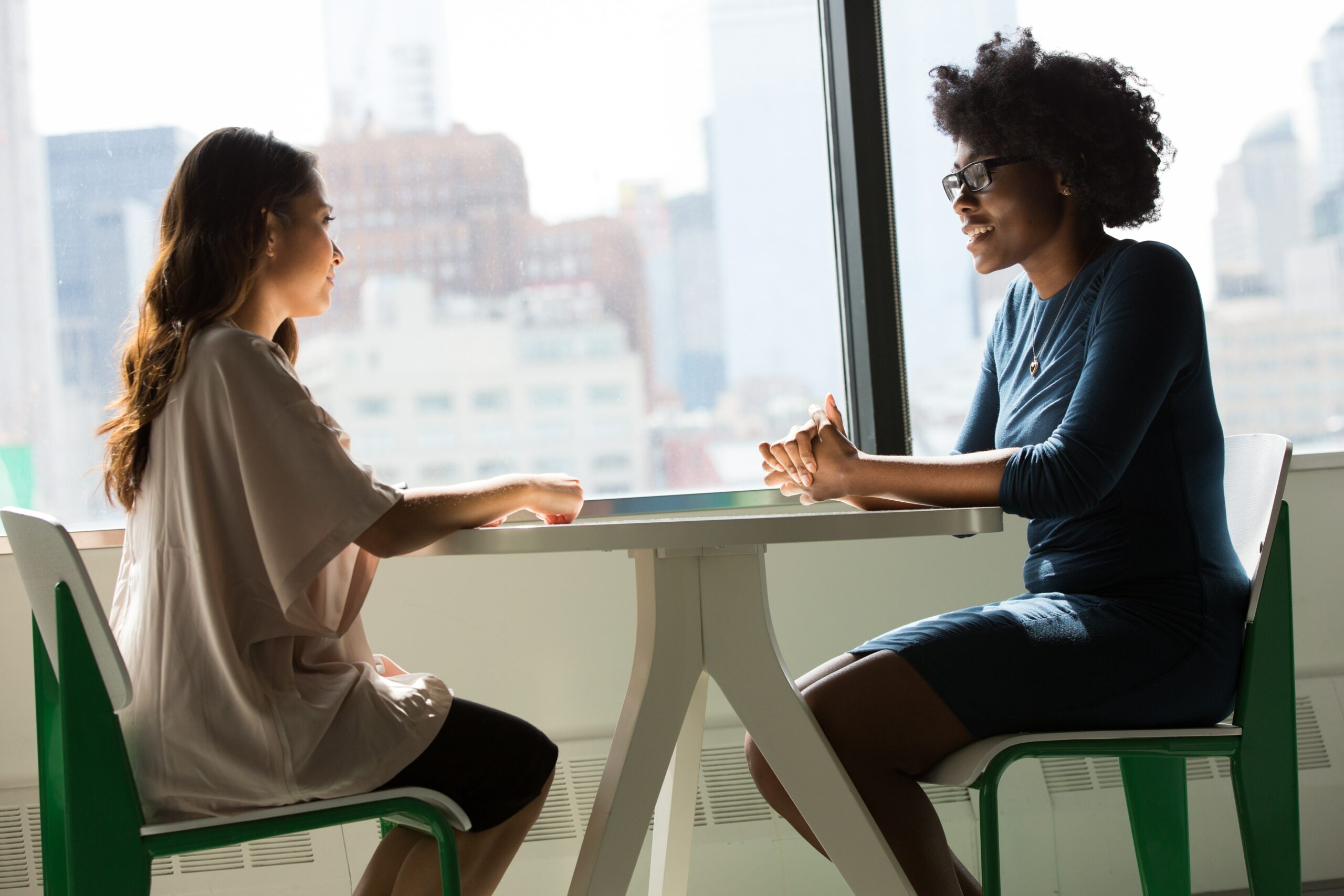 Dos mujeres sentadas teniendo una conversación, representando a dos personas hablando sobre cómo hacer crecer nuevas empresas.