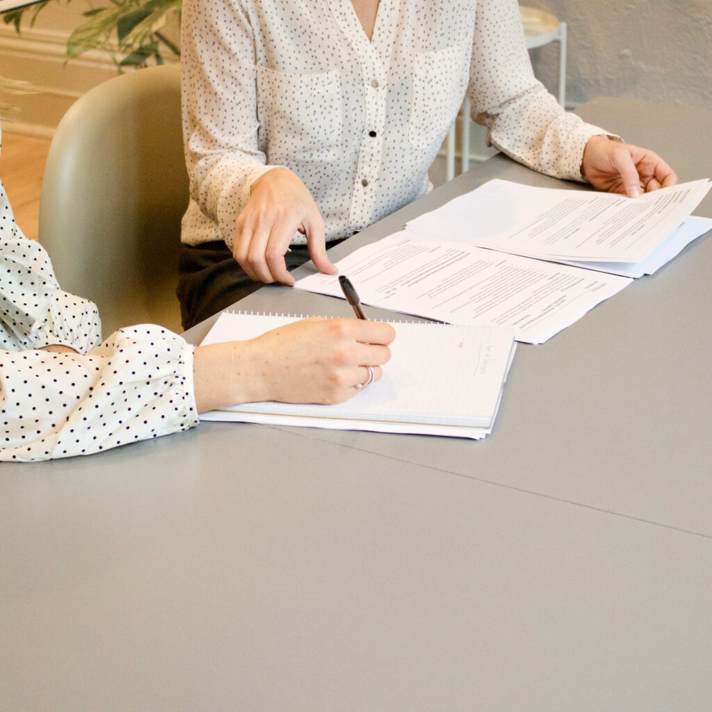 Imagen de stock representando a dos mujeres tomando apuntes en una reunión de trabajo.